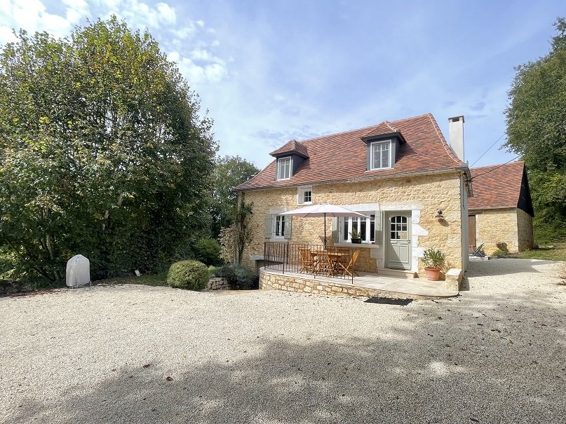 Maison en pierre avec grange nichée dans la verdure.